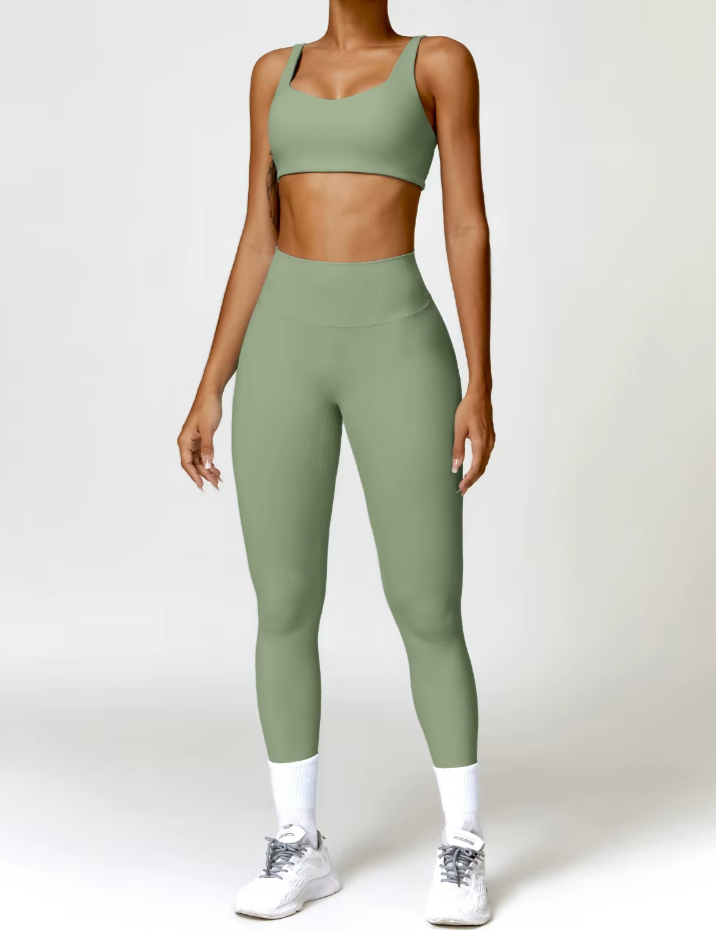 Femme portant l’ensemble Bella coloris vert sauge, de face – legging taille mi-haute et brassière à larges bretelles.