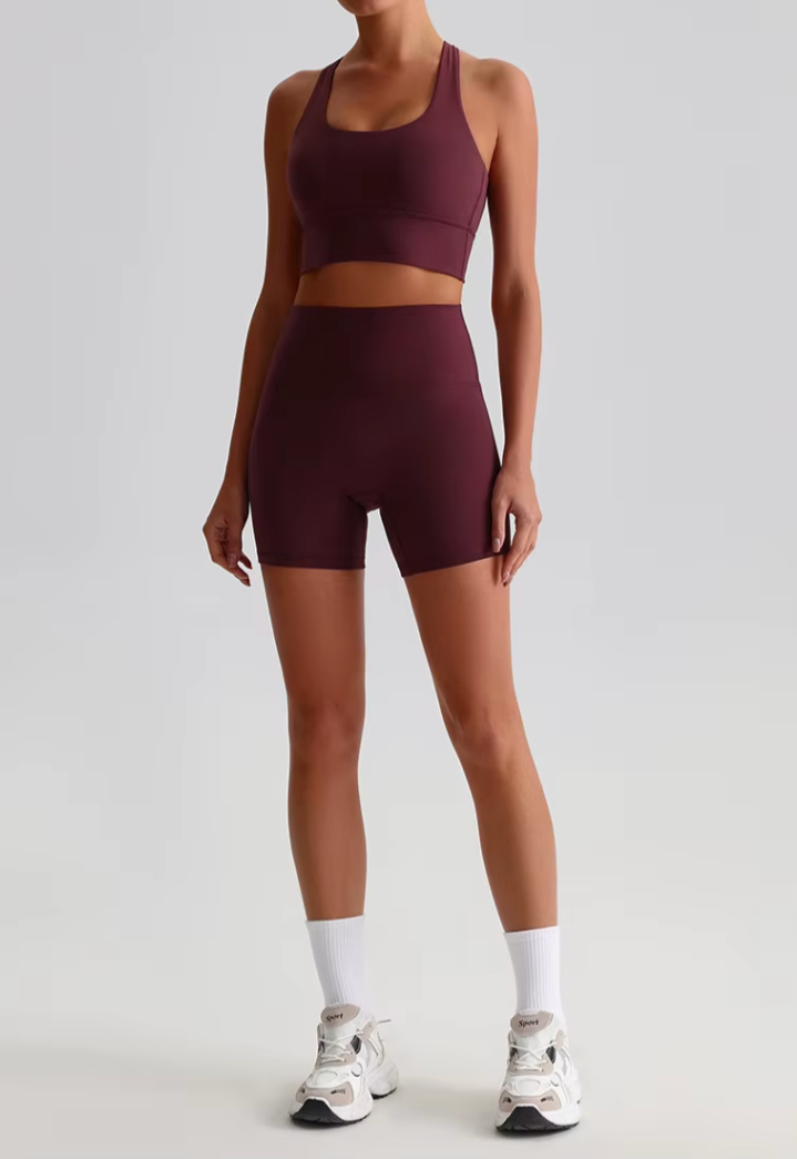 Femme de face en bordeaux, bras le long du corps, illustrant la coupe ajustée du short et le maintien de la brassière.