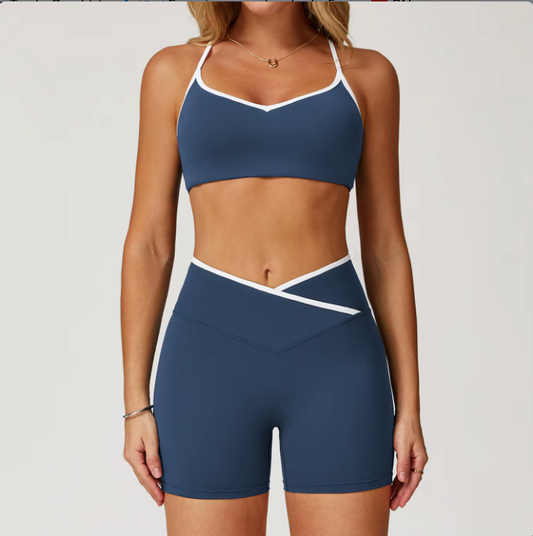 Femme portant l'ensemble Stella bleu marine avec brassière à fines bretelles et short taille haute à ceinture croisée, vue de face – tenue de sport élégante avec liseré blanc contrastant