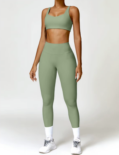 Femme portant l’ensemble Bella coloris vert sauge, de face – legging taille mi-haute et brassière à larges bretelles.
